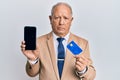 Senior caucasian man holding smartphone and credit card depressed and worry for distress, crying angry and afraid Royalty Free Stock Photo