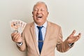 Senior caucasian man holding united kingdom pounds celebrating achievement with happy smile and winner expression with raised hand