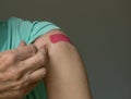 Senior man holding up shirt after covid-19 vaccine injection