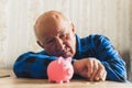 senior Caucasian man looking at the piggy bank medium closeup indoor financial problem concept Royalty Free Stock Photo