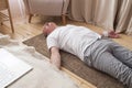 Senior man meditating on a wooden floor of living room and lying in Shavasana Royalty Free Stock Photo