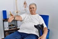 Senior caucasian man at physiotherapy clinic holding crutches smiling friendly offering handshake as greeting and welcoming Royalty Free Stock Photo