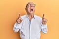 Senior caucasian man pointing up with fingers angry and mad screaming frustrated and furious, shouting with anger looking up Royalty Free Stock Photo