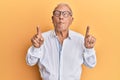 Senior caucasian man pointing up with fingers making fish face with mouth and squinting eyes, crazy and comical Royalty Free Stock Photo