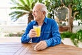 Senior caucasian man smiling happy drinking orange juice sitting on the table at terrace Royalty Free Stock Photo