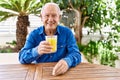 Senior caucasian man smiling happy drinking orange juice sitting on the table at terrace Royalty Free Stock Photo