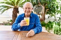 Senior caucasian man smiling happy drinking orange juice sitting on the table at terrace Royalty Free Stock Photo
