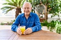 Senior caucasian man smiling happy drinking orange juice sitting on the table at terrace Royalty Free Stock Photo