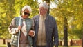 Senior Caucasian man walks with his blind wife in glasses and stick in the park disabled blind people support concept Royalty Free Stock Photo