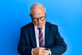 Senior caucasian man wearing business suit and tie checking the time on wrist watch, relaxed and confident Royalty Free Stock Photo