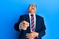 Senior caucasian man wearing business suit and tie laughing at you, pointing finger to the camera with hand over body, shame Royalty Free Stock Photo