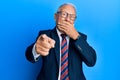 Senior caucasian man wearing business suit and tie laughing at you, pointing finger to the camera with hand over mouth, shame Royalty Free Stock Photo