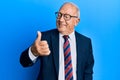 Senior caucasian man wearing business suit and tie looking proud, smiling doing thumbs up gesture to the side Royalty Free Stock Photo