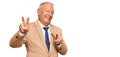 Senior caucasian man wearing business suit and tie smiling looking to the camera showing fingers doing victory sign Royalty Free Stock Photo