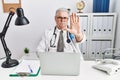 Senior caucasian man wearing doctor uniform and stethoscope at the clinic doing stop sing with palm of the hand Royalty Free Stock Photo