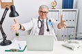 Senior caucasian man wearing doctor uniform and stethoscope at the clinic looking at the camera smiling with open arms for hug Royalty Free Stock Photo