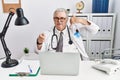 Senior caucasian man wearing doctor uniform and stethoscope at the clinic smiling doing talking on the telephone gesture and Royalty Free Stock Photo