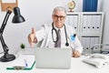 Senior caucasian man wearing doctor uniform and stethoscope at the clinic smiling friendly offering handshake as greeting and Royalty Free Stock Photo