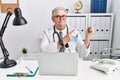 Senior caucasian man wearing doctor uniform and stethoscope at the clinic smiling and looking at the camera pointing with two Royalty Free Stock Photo