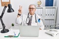 Senior caucasian man wearing doctor uniform and stethoscope at the clinic smiling looking to the camera showing fingers doing Royalty Free Stock Photo