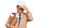 Senior caucasian man wearing safety helmet holding blueprints stressed and frustrated with hand on head, surprised and angry face Royalty Free Stock Photo