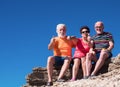 Senior caucasian people sitting on the cliffs smiling and gesturing up and down. Enjoying free time and retirement