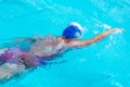 Senior caucasian woman in activity swimming in freestyle stroke. Pratice sport in the swimming pool. Outdoor under the sunlight.