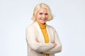 Senior caucasian woman with blonde hair in white and yellow sweater smiling