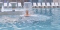 Senior caucasian woman enjoying falling jets of water in outdoor thermal swimming pool