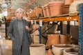 Aged woman choosing earthenware crockery in store