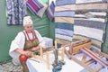 Senior Caucasian woman in traditional Russian dress weaving colorful striped rug on hand loom Royalty Free Stock Photo