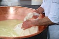 Senior cheesemaker collects the cheese with the tarp from the co