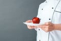 Senior chef studio standing isolated on gray with apple on plate close-up