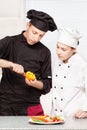 Senior chef teaches young chef to decorate fruit Royalty Free Stock Photo