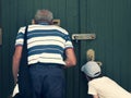 Senior and child are looking through the mail slot and keyhole. Concept of two generations, peeping and peeking