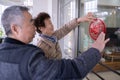 A Senior Chinese woman and man pasting the traditional `Fu` character paper cut on a glass door at home, for Chinese New Year