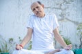 Senior Citizen or an Old Indian Man Performing Yoga Early Morning, in his Terrace in white Tshirt and Pants. Stay Home Stay Safe a Royalty Free Stock Photo