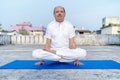 Senior Citizen or an Old Indian Man Performing Yoga Early Morning, in his Terrace in white Tshirt and Pants. Stay Home Stay Safe a Royalty Free Stock Photo