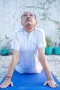 Senior Citizen or an Old Indian Man Performing Yoga Early Morning, in his Terrace in white Tshirt and Pants. Stay Home Stay Safe a Royalty Free Stock Photo