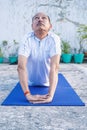 Senior Citizen or an Old Indian Man Performing Yoga Early Morning, in his Terrace in white Tshirt and Pants. Stay Home Stay Safe a Royalty Free Stock Photo