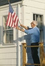 Senior citizen raising the American flag on house in Stonington, Maine