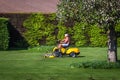 Senior citizen riding lawn mower in a garden Royalty Free Stock Photo