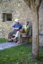 Senior citizens resting and making cell phone call on Plaza Mayor, in Ainsa, Huesca, Spain in Pyrenees Mountains, an old walled to Royalty Free Stock Photo