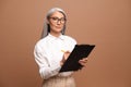 Senior confident business woman writing at the clipboard and looking at the camera. Mature female employee in formal Royalty Free Stock Photo