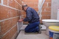 Senior constructor worker laying white ceramic tiles on the wall. Royalty Free Stock Photo