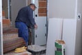 Senior constructor worker preparing tile adhesive mortar with a hand mixer.