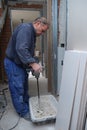 Senior constructor worker preparing tile adhesive mortar with a hand mixer.