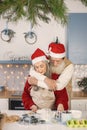 Senior couple in aprons and christmas red hats baking cookies in kitchen Royalty Free Stock Photo