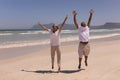Senior couple with arms up jumping on beach Royalty Free Stock Photo