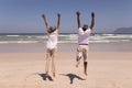 Senior couple with arms up jumping on beach Royalty Free Stock Photo